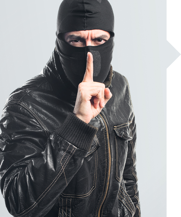 Masked figure in black leather jacket making shushing gesture